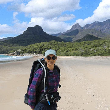 A Khaki and Ocean founder on a sandy beach with mountains behind